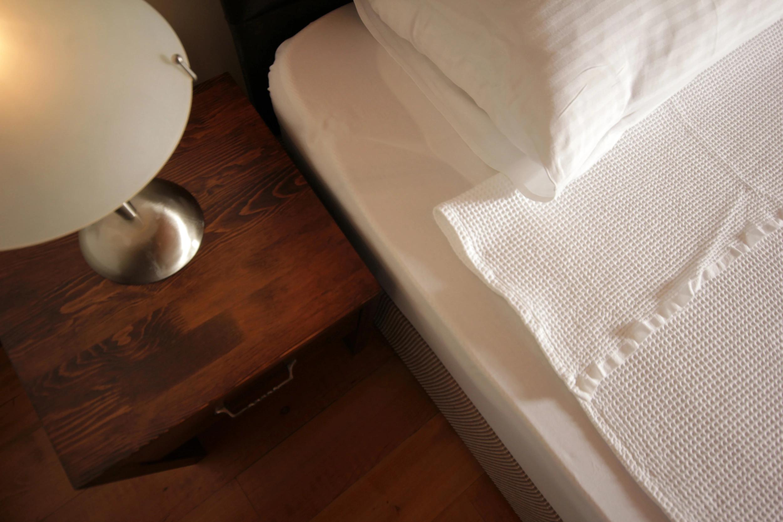 Détail de la literie et table de chevet dans une chambre de l'hôtel 4 étoiles San Andrea